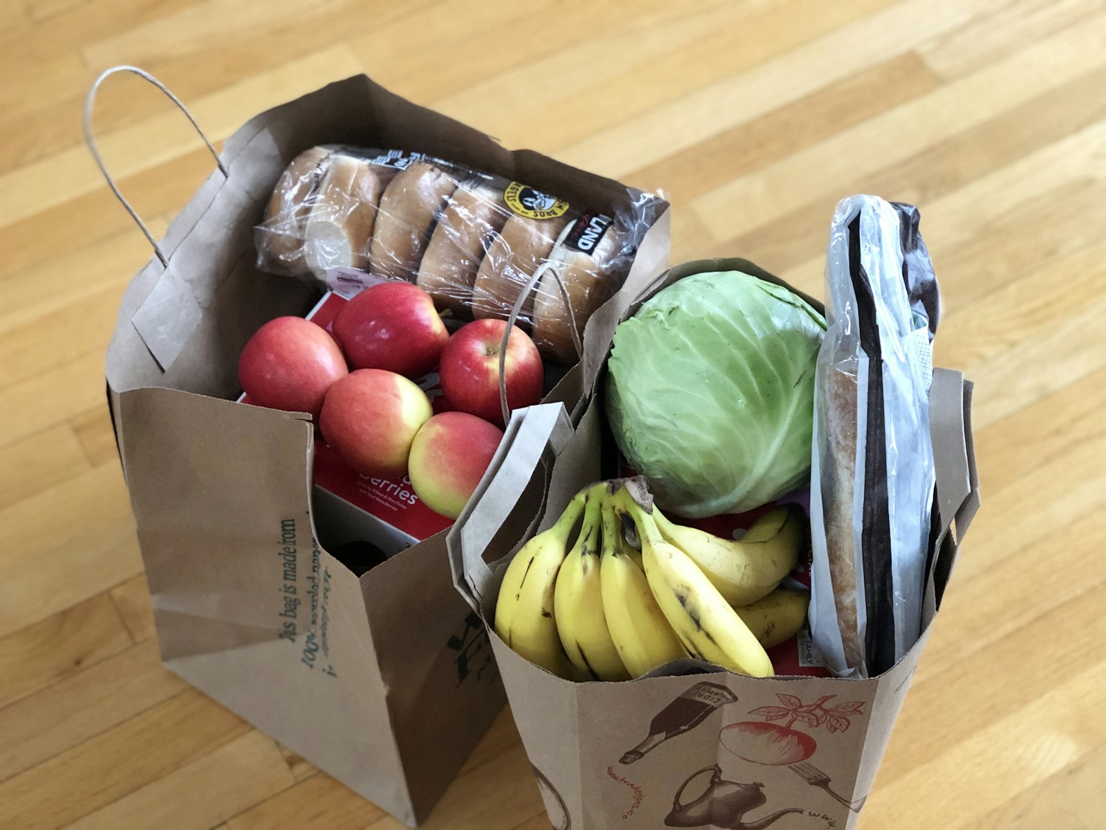 Paper grocery bags filled with produce and bread